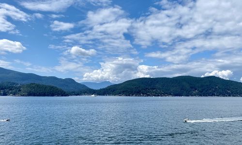 Scenic view of sea by mountains against sky