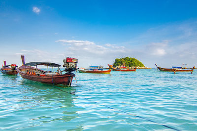 Boats moored in sea against blue sky