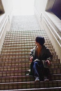 Low angle view of man sitting on staircase