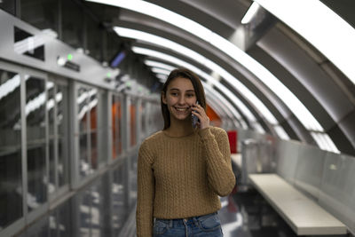 Young woman talking on the phone at the subway station.