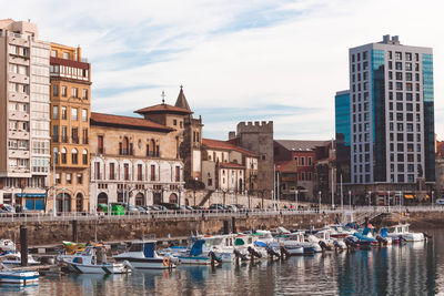 Boats moored in canal against buildings in city