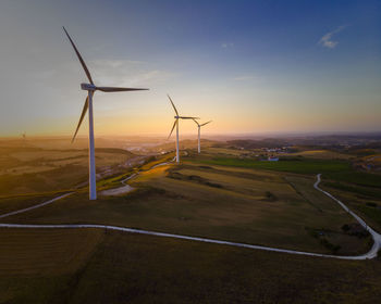 Windmill on field against sky during sunset