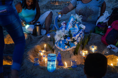 People sitting by illuminated decoration on sand