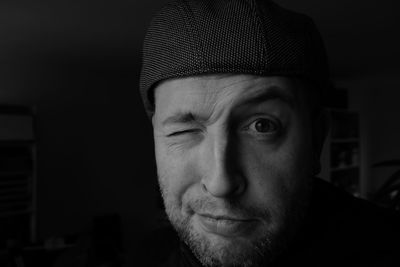 Close-up portrait of man winking in darkroom