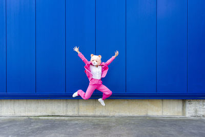 Full length of woman with arms raised against wall