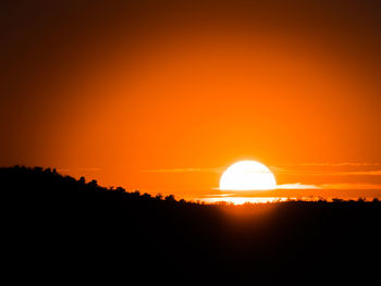 Scenic view of silhouette landscape against orange sky