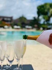 Close-up of champagne flute on table against swimming pool