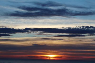 Scenic view of sea against dramatic sky during sunset