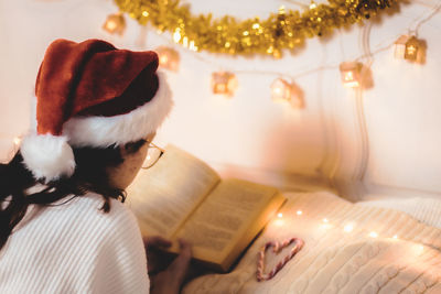 The girl is reading a book lying on the bed.