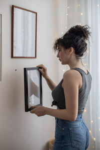 Woman looking at camera while standing against wall