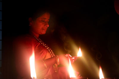 Man looking at lit candle in the dark