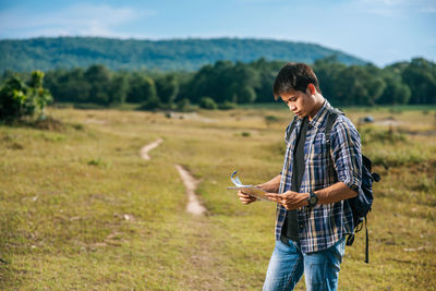 Young man using mobile phone on field