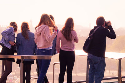 Rear view of people photographing against sky