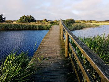 Boardwalk amidst lake against sky