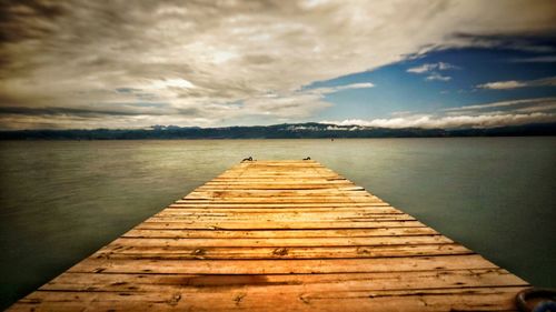 Pier on lake against cloudy sky