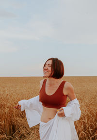 Side view of woman standing on field against sky