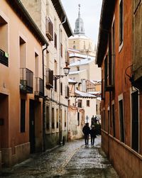 Rear view of people walking in alley amidst buildings