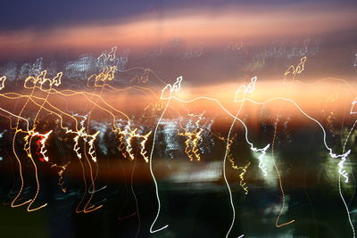 Close-up of illuminated spider web against sky at night