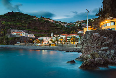 Buildings by sea against sky