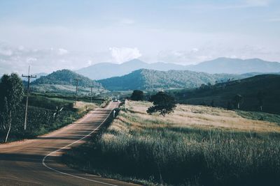 Road leading towards mountains against sky