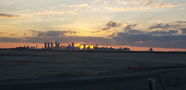 Scenic view of sea and buildings against sky during sunset