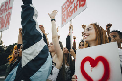 Low angle view of smiling women protesting with banners in city