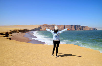 Female visitor being impressed by the red beach or playa roja of paracas national reserve, peru