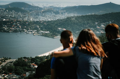 Rear view of people looking at sea by city