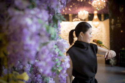 Asian woman holding sun conure parrot on hand