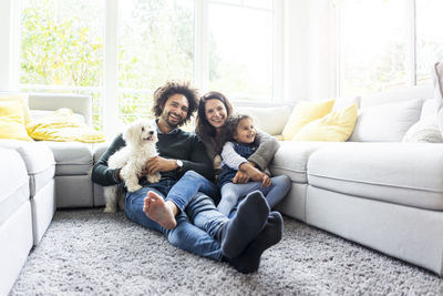 Happy family with dog sitting together in cozy living room