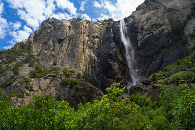 Low angle view of waterfall on rocks against sky