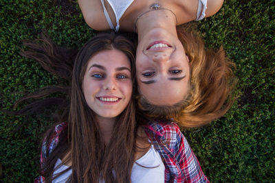 Portrait of smiling female friends lying down on field