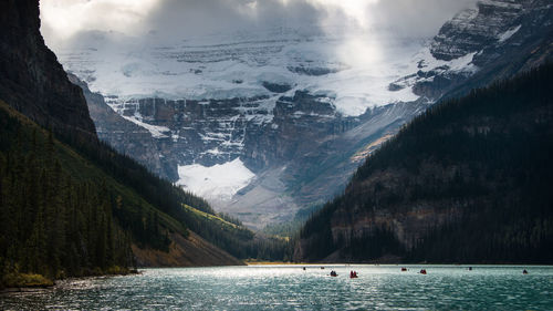 Scenic view of lake by snowcapped mountains against sky