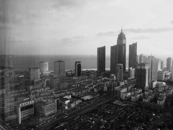 High angle view of city buildings against cloudy sky