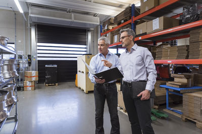 Two businessmen in factory hall talking