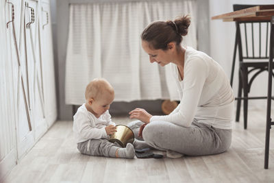 Mother plays with her son baby on the floor in a real bright interior, the concept of motherhood 