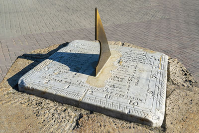 A close-up sundial on the street shows the time