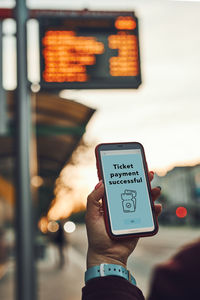 Buying ticket online near bus stop before ride. person paying for ticket using mobile payment app