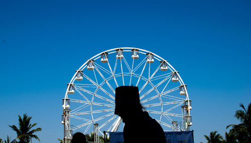 Low angle view of silhouette ferris wheel against clear blue sky