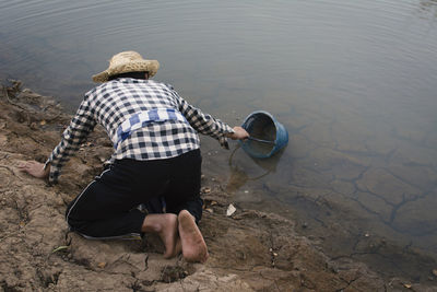 Man taking water in bucket from lake
