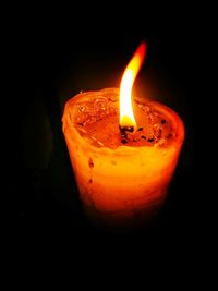 Close-up of lit candle in darkroom