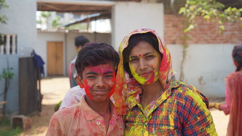 Outdoor image of asian, indian happy mother son in indian dress celebrating the holi festival 