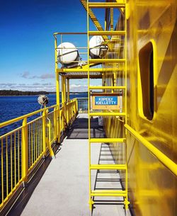 Yellow staircase by sea against sky