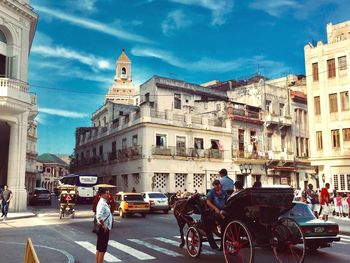 People on city street by buildings against sky