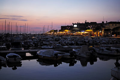 Sailboats moored at harbor against sky during sunset