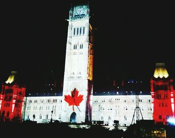 Low angle view of clock tower at night