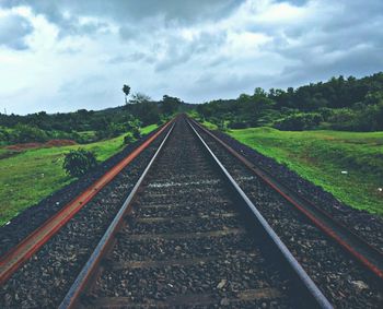 Railroad tracks against cloudy sky