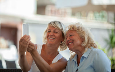 Smiling friends taking selfie at sidewalk cafe