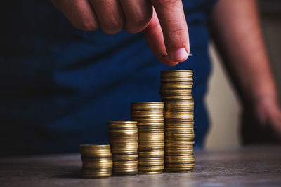 Close-up of hand stacking coins on table