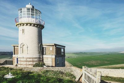 Lighthouse by landscape against sky